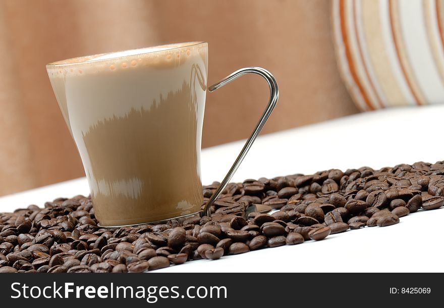 A cup of cappuccino and roasted coffee beans