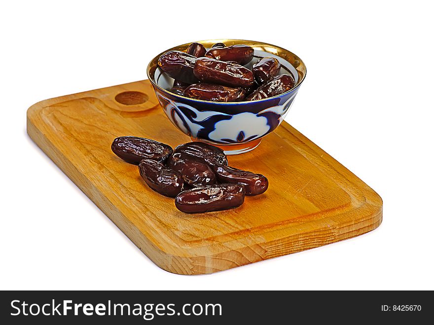 Dates in  cup on wooden plate. Dates in  cup on wooden plate