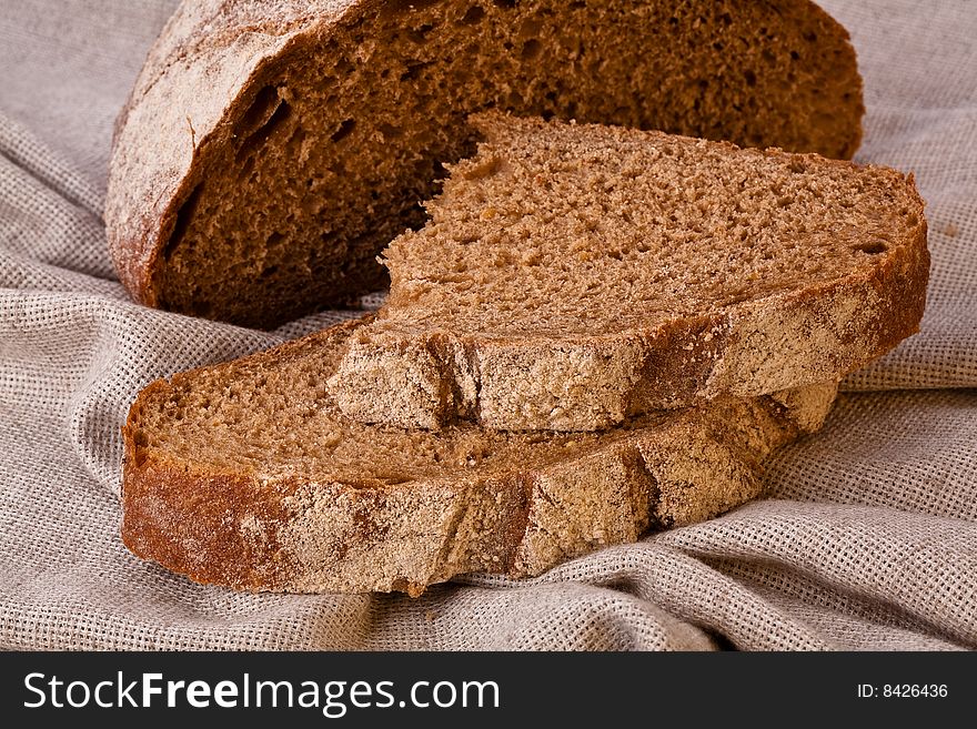 Sliced rustic brown bread loaf on the table covered with canvas tablecloth