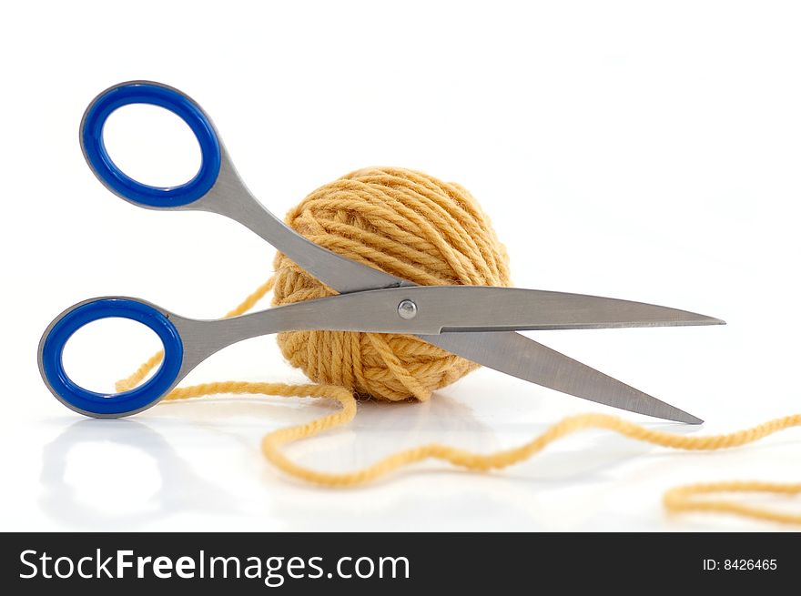 Ball with yarn and scissors against the white background