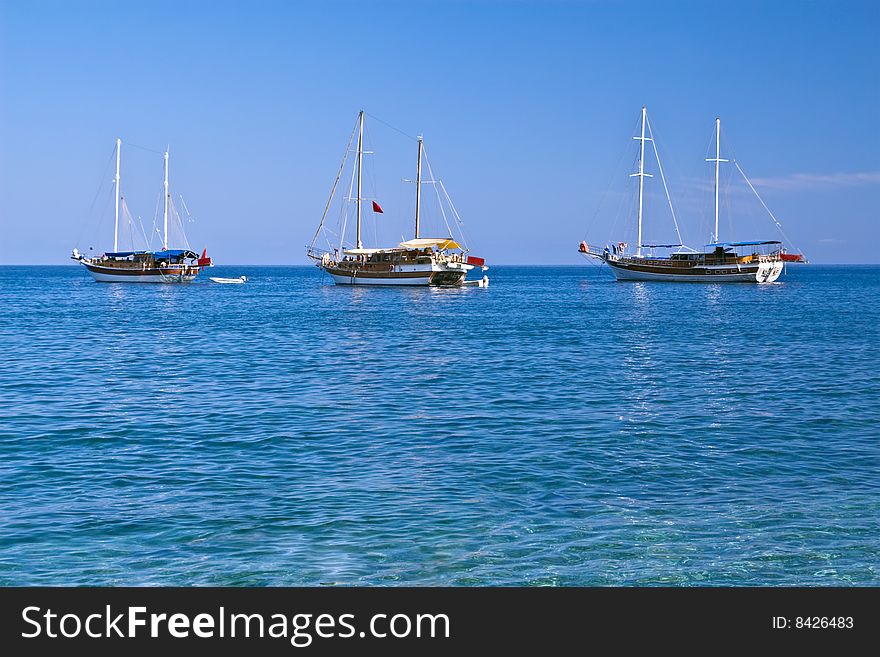Three sailboats with lowered sails in sunny weather, with copyspace. Three sailboats with lowered sails in sunny weather, with copyspace