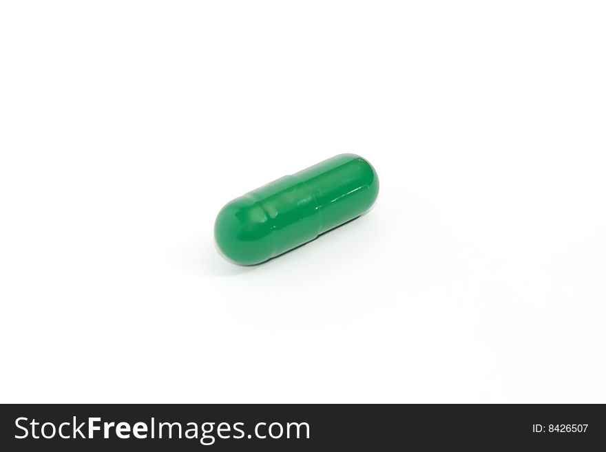 Closeup of a green capsule on the white backgound. Closeup of a green capsule on the white backgound