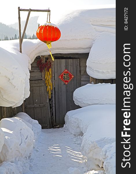 A red lantern  and a house covered in snow