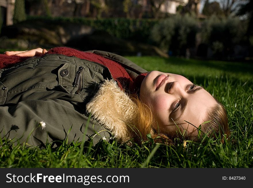 Girl in a red sweater, in a jacket on a green grass. Girl in a red sweater, in a jacket on a green grass