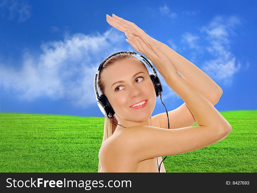 Portrait of happiness young women with beautiful face in headphones and listening music on the blue sky and green grass background. Portrait of happiness young women with beautiful face in headphones and listening music on the blue sky and green grass background