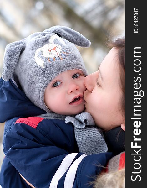 Portrait of young mother kissing small son outdoors. Portrait of young mother kissing small son outdoors