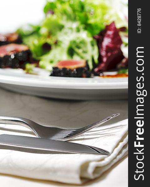 Fork and Knife with Salad on a Background. Selective Focus