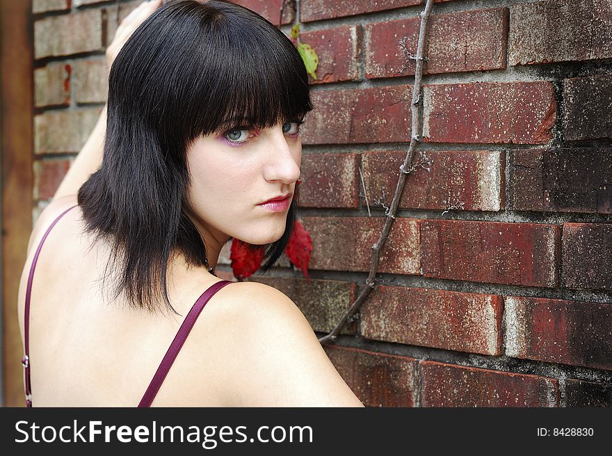 Young woman facing camera and standing in front of wall with upset look on her face. Young woman facing camera and standing in front of wall with upset look on her face