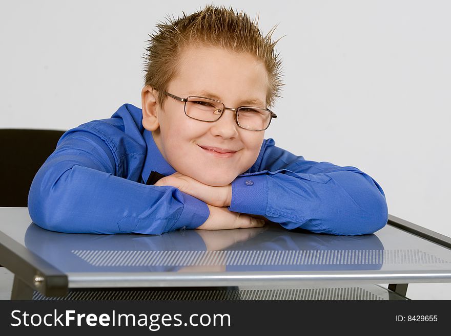 Funny schoolboy leaning on school desk