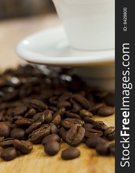 Coffee beans on the table with white coffee cup. Shallow dof.