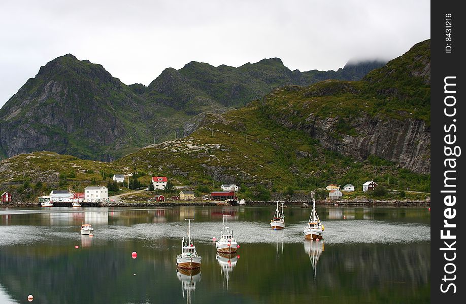 A small fishing port in the lofoten islands with boats reflected in the sea, Norway. A small fishing port in the lofoten islands with boats reflected in the sea, Norway
