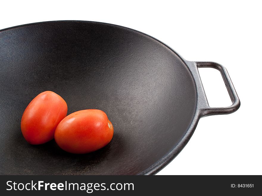 Two roma tomatoes in a black cast iron wok. Two roma tomatoes in a black cast iron wok