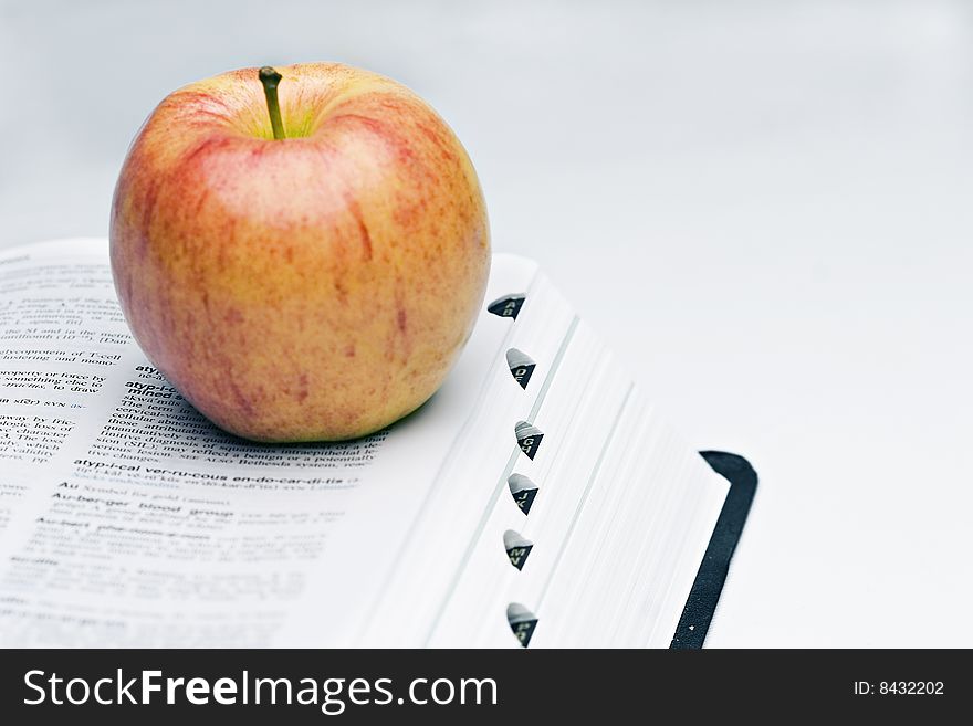 Isolated shot of apple on top of an open book. Isolated shot of apple on top of an open book