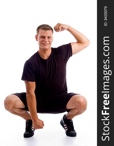 Sitting muscular man showing his muscles against white background