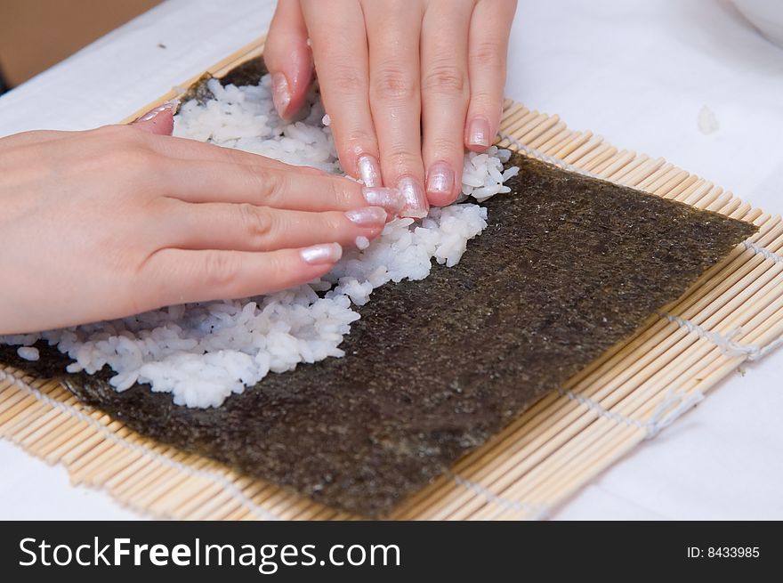 Girl cooking sushi, rice with nori