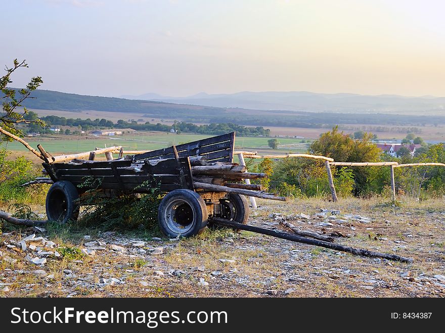 Old cart with fire wood against a rural landscape
