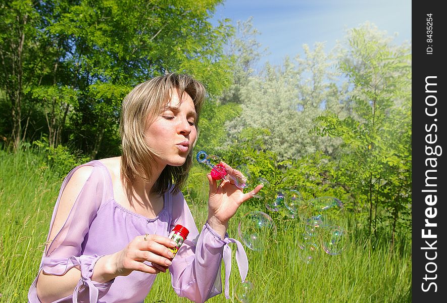 Cute young woman blows a soap bubbles