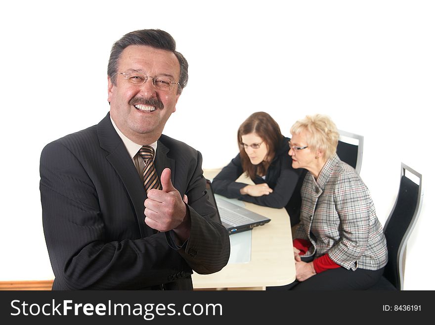 Businessman showing tumb up sign in office environment. Three people with focus on mature man in front. Isolated over white. Businessman showing tumb up sign in office environment. Three people with focus on mature man in front. Isolated over white.