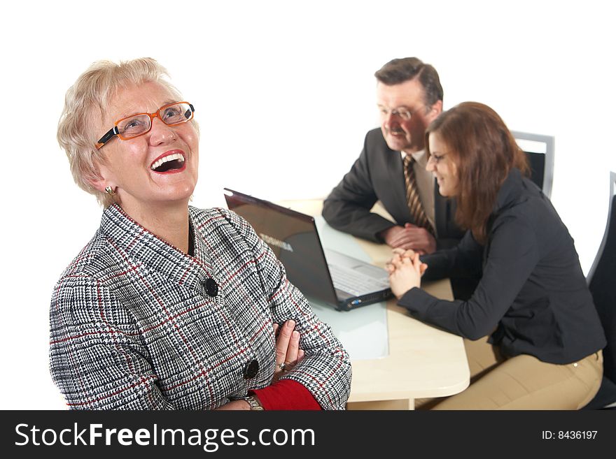 Businesswoman laughing in office environment. Three people with focus on mature woman in front. Isolated over white. Businesswoman laughing in office environment. Three people with focus on mature woman in front. Isolated over white.