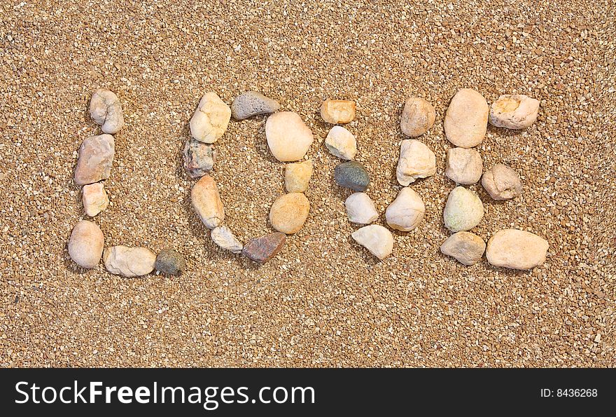 Love written in the sand using stones. Love written in the sand using stones