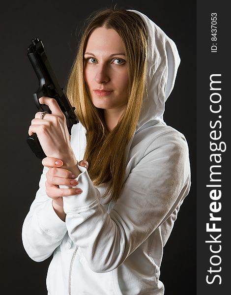 Girl in a white loose overall with gun on a dark background. Girl in a white loose overall with gun on a dark background