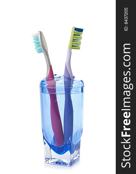 Two colorful toothbrushes in glass isolated