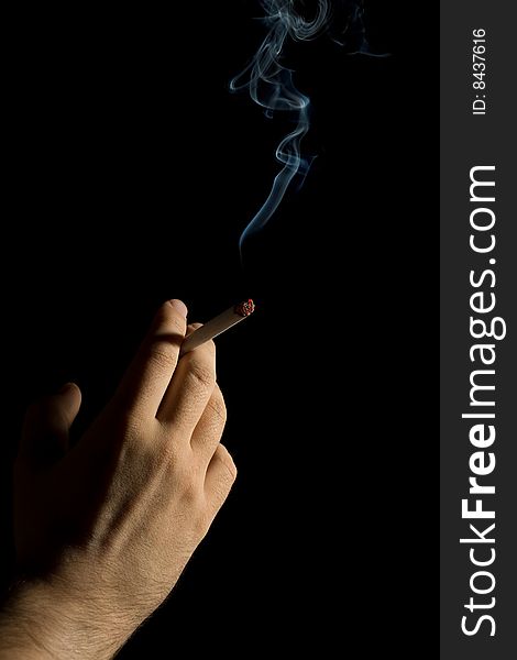 Hand holding a smoking cigarette isolated on black