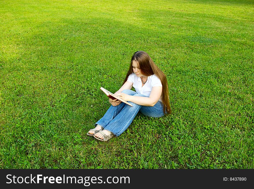 Blond girl reading red book over the grass. Blond girl reading red book over the grass