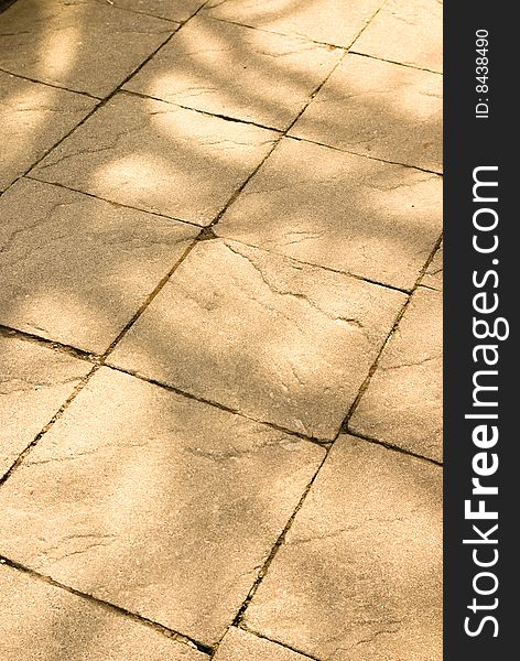 Dappled light on stone texture of path or sidewalk as background for spring or summer