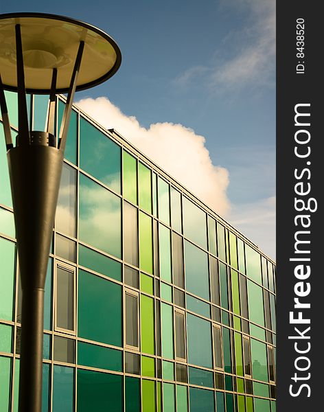 Brightly coloured modern building and streetlamp against blue sky and clouds