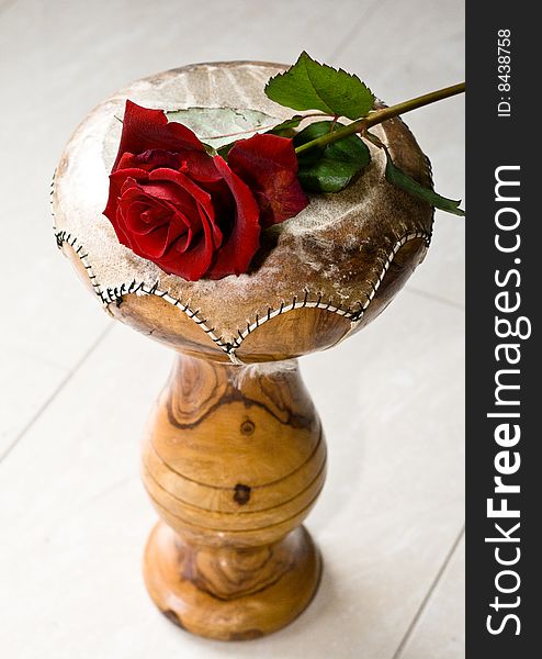 A red rose laying on a Indian drum instrument. A red rose laying on a Indian drum instrument