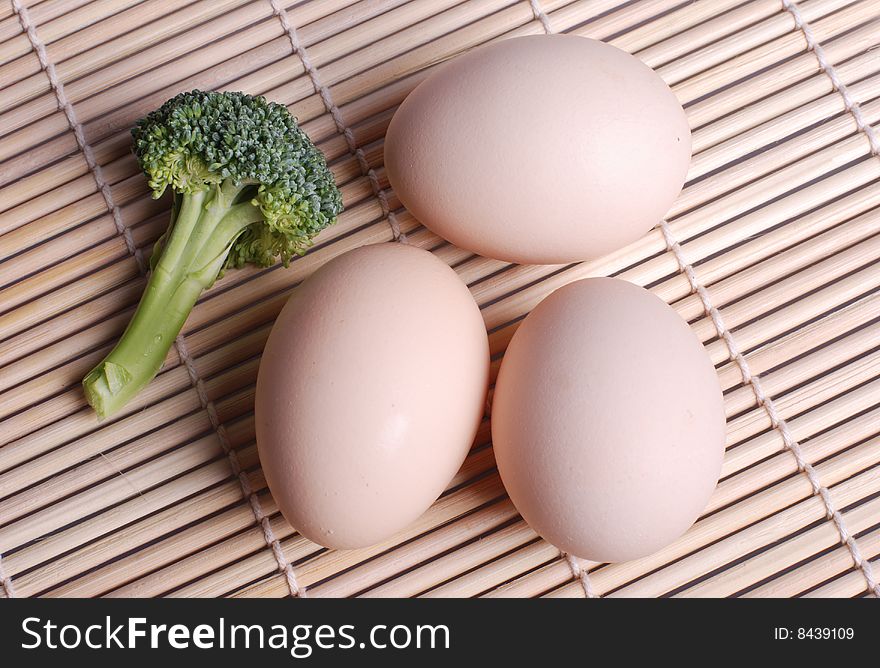 Three eggs and broccoli lying down on bamboo chick