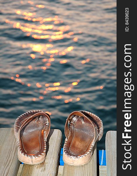 Leather sandals standing on water edge in sunset light. Leather sandals standing on water edge in sunset light