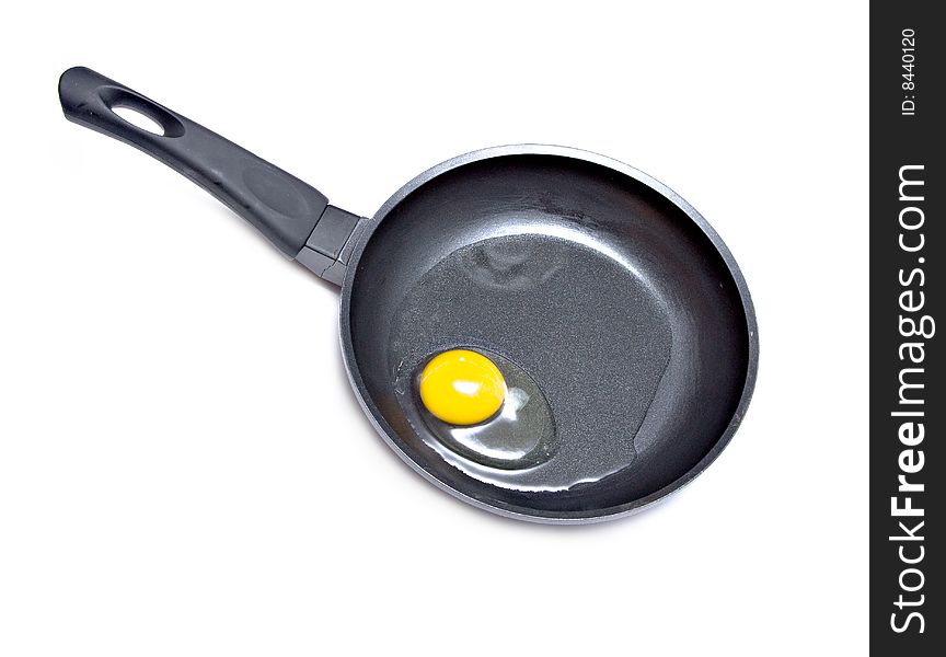 A raw egg in a frying pan on white background. A raw egg in a frying pan on white background.