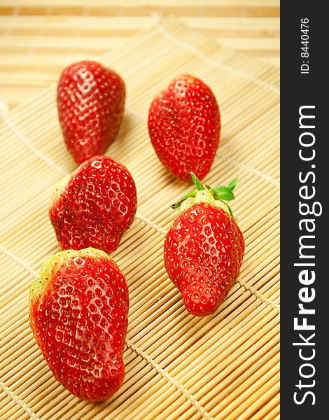Close-up of strawberries in rows on a bamboo mat. Close-up of strawberries in rows on a bamboo mat