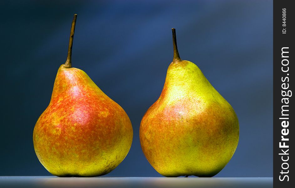 Two pears standing on a table on a dark background. Two pears standing on a table on a dark background