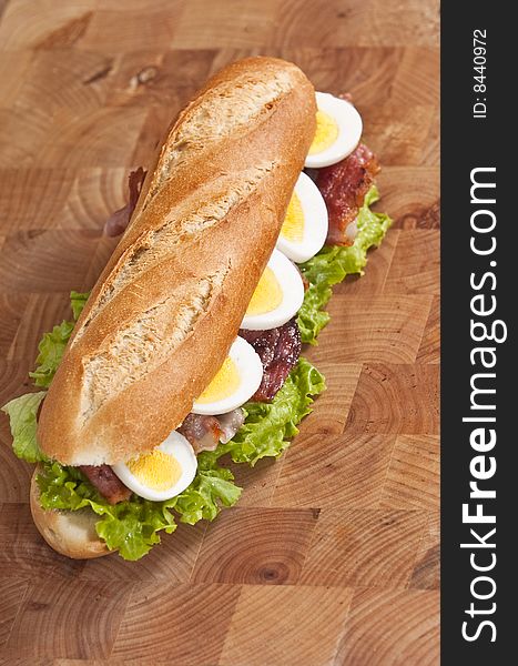 Bacon and egg sandwich on wooden board