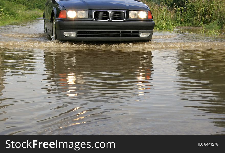 Water splashes from under the wheels, dangerous ride of the car through large water, flood, reckless driving, driving through a river overflow, water on road after downpour, obstacle course, come encounter an obstacle