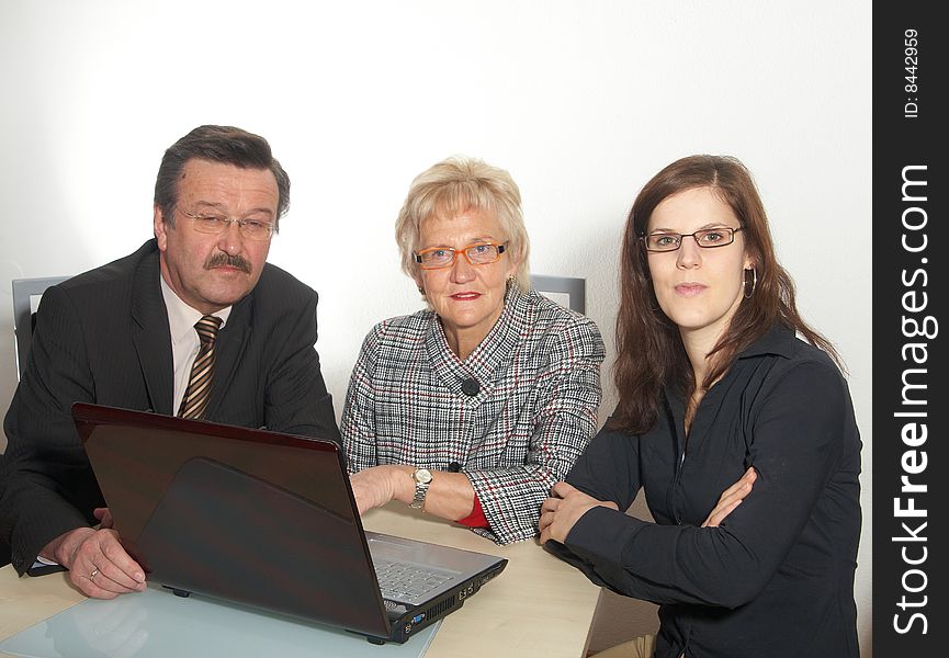 A business team of three sitting in front of a laptop. Isolated over white. A business team of three sitting in front of a laptop. Isolated over white.