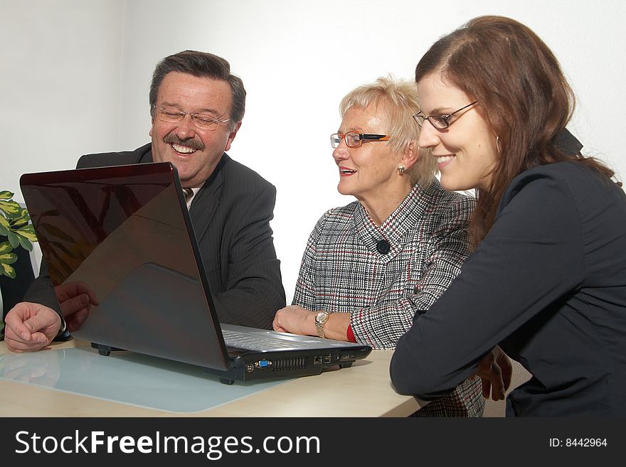A business team of three sitting in front of a laptop. Focus is on the man in the back. Isolated over white. A business team of three sitting in front of a laptop. Focus is on the man in the back. Isolated over white.