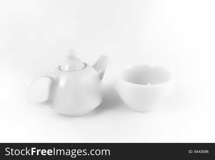 White teapot and teacup on the white light background. White teapot and teacup on the white light background