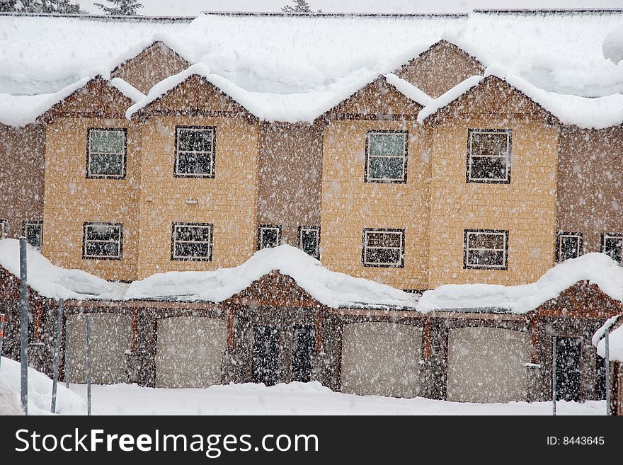 A group of modern looking row houses are getting snowed on with large flakes in Government Camp Oregon. A group of modern looking row houses are getting snowed on with large flakes in Government Camp Oregon.