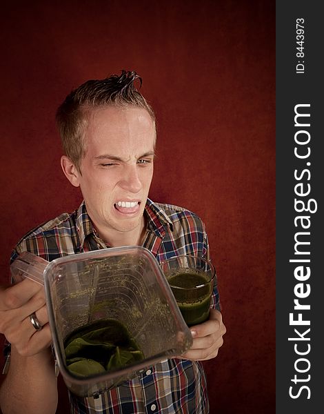 Young man grimacing and holding unappetizing blended health shake. Young man grimacing and holding unappetizing blended health shake