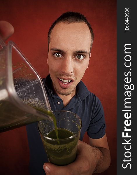 Young man holding unappetizing blended health shake. Young man holding unappetizing blended health shake