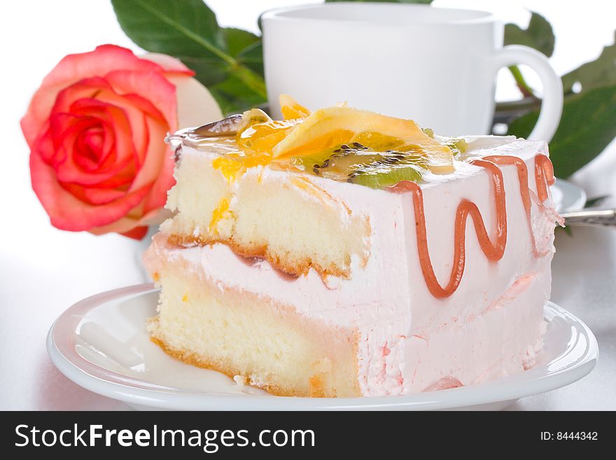 Piece of cake with fruits rose and cup, isolated on white