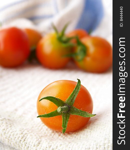 Image of small, bright tomatoes on white kitchen linen. Image of small, bright tomatoes on white kitchen linen.