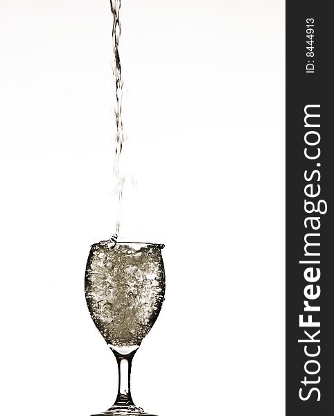 A stream of water splashing into and filling a wine glass. A stream of water splashing into and filling a wine glass.