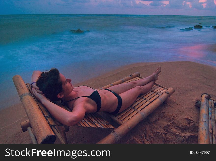 View of a woman lounging in hammock / chaise long during sunset. View of a woman lounging in hammock / chaise long during sunset