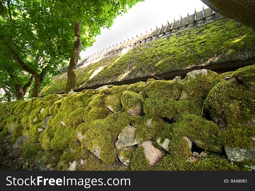 Thatched roof and rock fence is covered by moss in beautiful day. Thatched roof and rock fence is covered by moss in beautiful day