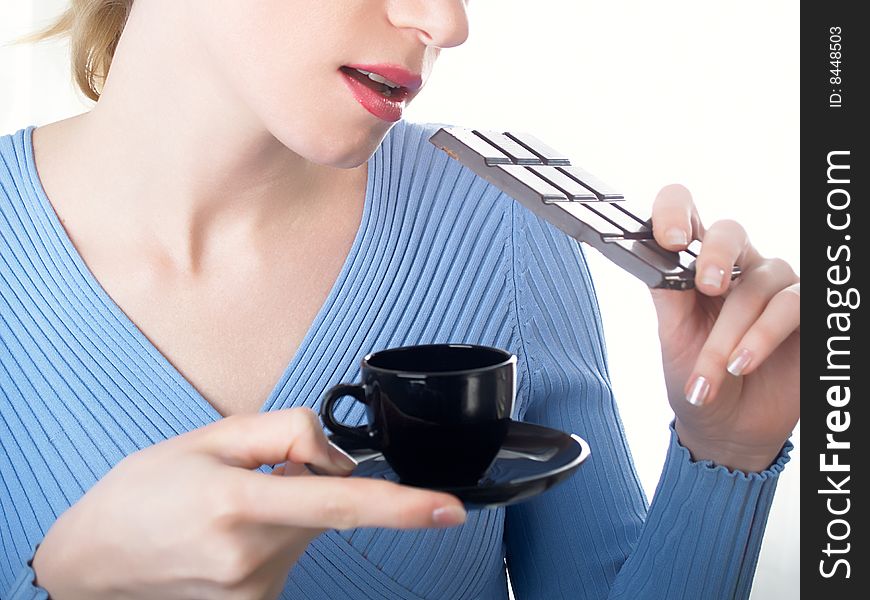 The beautiful girl with a coffee cup in a hand and chocolate